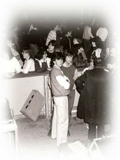 an old black and white photo of people standing in front of a counter with luggage