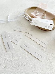 some white tags are sitting on a table next to a bowl with flowers and other items