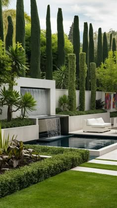 an outdoor pool surrounded by greenery and water features in the background is a white lounge chair