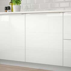 a kitchen with white cabinets and a potted plant on top of the cabinet doors