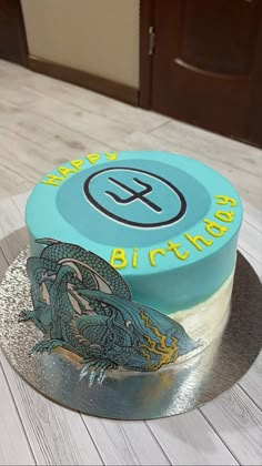 a birthday cake with a dragon on the top and blue frosting is sitting on a silver platter