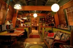 the inside of a restaurant with wooden tables and couches, lights hanging from the ceiling