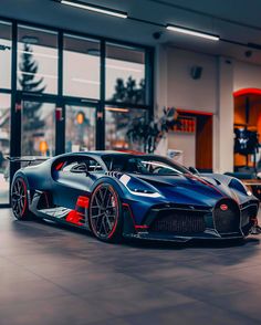 the bugatti supercar is parked in front of a large glass building with lots of windows