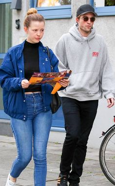 a man and woman are walking down the street with an orange object in their hand