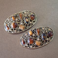 ♥Vintage signed MUSI shoe clips featuring the design of an oval antique gold tone metal design embellished with faux tortoise shell cabochons as well as small pale brown rhinestones. These clips measure 2 5/8" x 1 3/8". Shoe clips have been around since the 18th century but were most popular during the first half of the 20th century, and they have made quite the comeback. Shoe clips were a way to add versatility and style having the ability to adapt a single pair of shoes to fit a variety of clothing styles. That statement still holds true to this day as well as being a budget friendly way to accessorize. These clips can even be worn as dress clips (and more creative uses) adding even more versatility to an already adaptable accessory. To see more vintage shoe clips in my shop, please clic Dress Clips, Vintage Shoe, Glendale Az, Dress Clip, Shoe Clips, Metal Design, Vintage Shoes, The 20th Century, Tortoise Shell