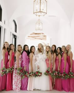 a group of women standing next to each other in long dresses and holding bouquets