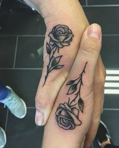 two people with matching tattoos on their hands holding each other's fingers, one has a flower and the other has a leaf