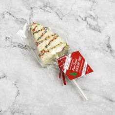 a white cake on a stick with sprinkles is wrapped in cellophane