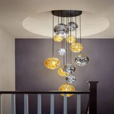 a chandelier hanging from the ceiling in a room with stairs and railings