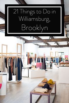 the inside of a clothing store with clothes hanging on racks and tables in front of it