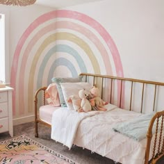 a child's bedroom with a rainbow painted on the wall and gold metal bed frame