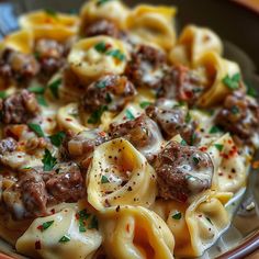 a close up of a plate of pasta with meat and cheese on it's surface