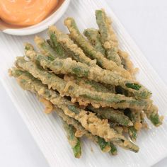 fried green beans on a plate with dipping sauce