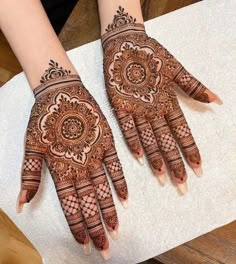 two hands with henna designs on them, one is showing it's intricate design