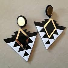 two black and white geometric earrings with gold accents on top of each earring, one in the shape of a triangle