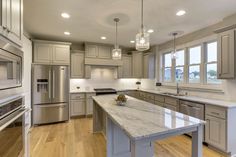 a large kitchen with an island in the middle and stainless steel appliances on both sides