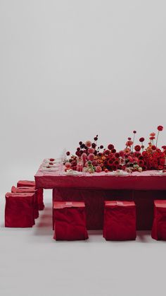 a table that has some red bags on it with flowers in the middle and other items around it