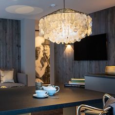 a table with two cups and saucers on it in front of a wall mounted television