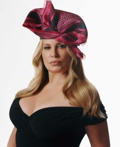 a woman in a black dress with a pink and black hat on top of her head