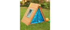 a cardboard play house in the grass with a ball and teepee on the ground