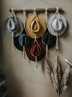 four hats hanging on a wall with string and hooks attached to it, one hat has a tear in the middle