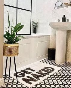 a black and white bathroom with a plant on the floor