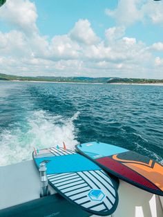 two surfboards sitting on the back of a boat in the open water near land