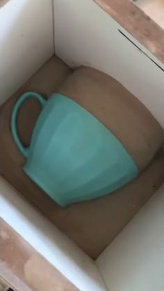 a teal cup sitting inside of a white box