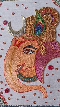 an embroidered cloth with the face of lord ganesh in gold, red and green colors