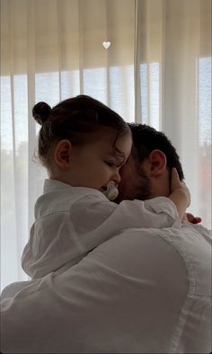 a man and woman laying in bed next to each other with their arms around each other