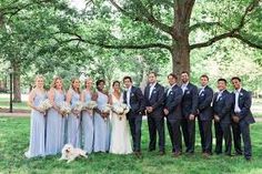 a group of people standing next to each other in front of a tree with a dog