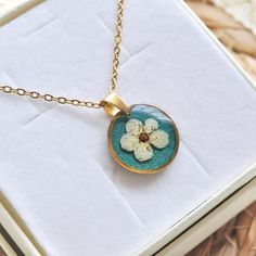 a necklace with a flower on it sitting in a box