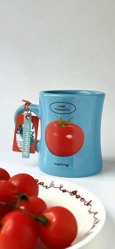 a blue coffee mug sitting on top of a white plate filled with red cherry tomatoes