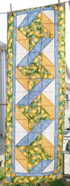 a quilt hanging from a clothes line with lemons and leaves in the center on it