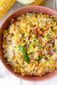 a bowl filled with corn and parmesan cheese on top of a marble counter