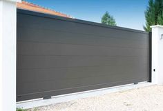 a large gray garage door next to a white fence