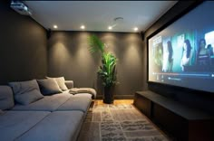 a living room with couches and a flat screen tv on the wall in front of it