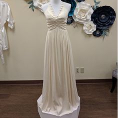 a dress on display in front of a wall with paper flowers and clothes hanging from it