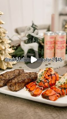 a white plate topped with meat and lobster next to a christmas tree on a table