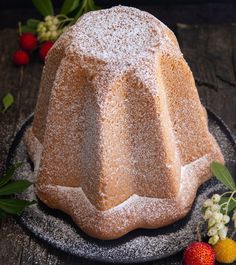 a cake with powdered sugar on top sitting on a plate next to strawberries