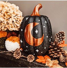 a painted pumpkin sitting on top of a mantle filled with pine cones and other autumn decorations