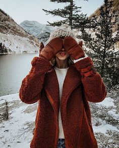 a woman standing in the snow holding her hands up to her face and covering her eyes