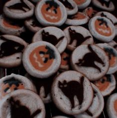 cookies decorated with orange and black icing are sitting on a cooling rack in front of the camera