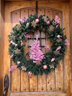 a christmas wreath is hanging on the front door with pink decorations and ornaments around it