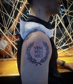 a man with a tattoo on his arm that reads vein vidi vici and has a laurel around it