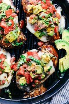 grilled chicken topped with avocado, tomatoes and other toppings on a grill