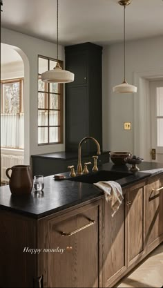 a kitchen with wooden cabinets and black counter tops, gold faucets and hanging lights