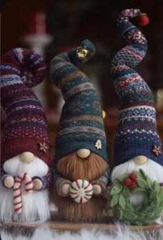 three knitted gnomes are standing next to each other with candy canes in their hands