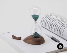 an hourglass and pen sitting on top of a book