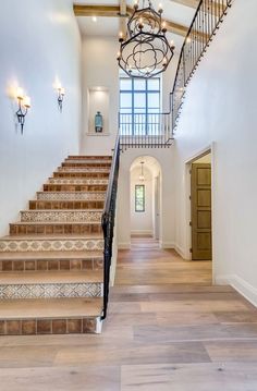 a staircase leading up to the second floor with chandelier and lights on either side